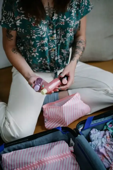 Frau die Fläschchen in eine Kosmetiktasche packt