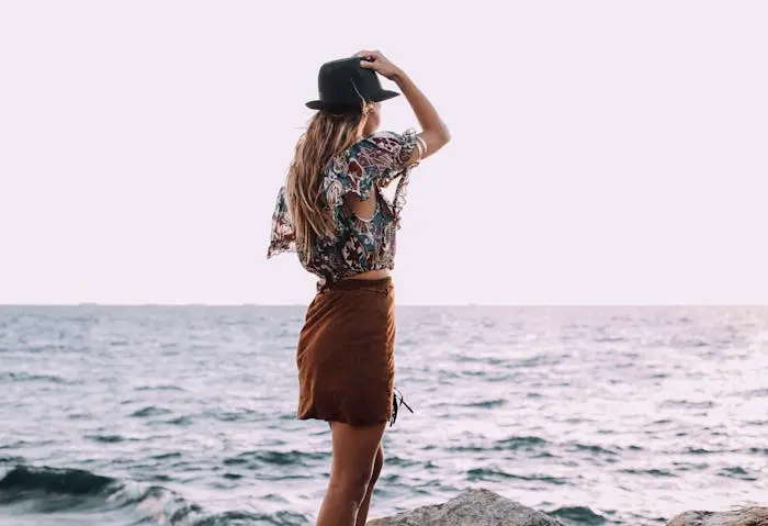 Frau steht in Sommerkleidung am Strand