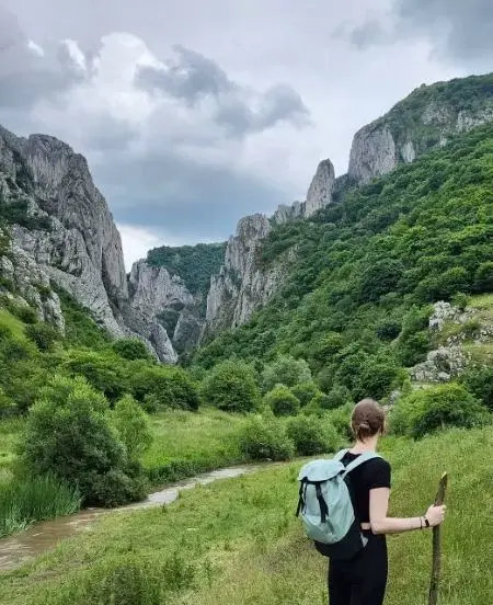 Frau mit Wanderstock und Rucksack vor Felsformationen
