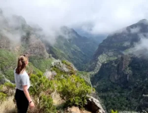 Frau schaut auf nebelverhangenes Bergtal