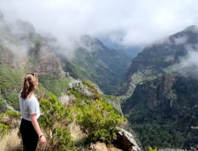 Frau schaut auf nebelverhangenes Bergtal